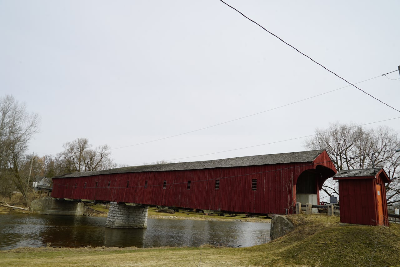 A red wooden covered bridge over a river