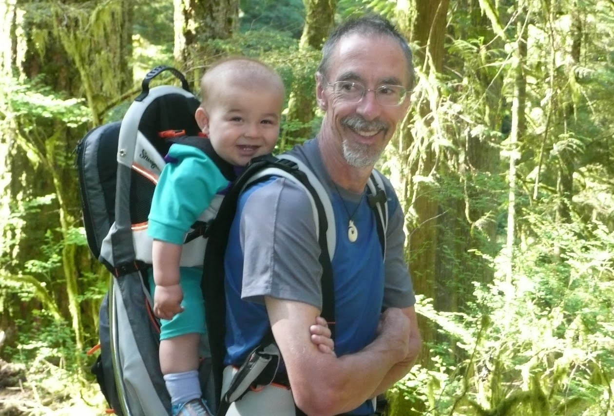 A man carrying a baby on a hike.