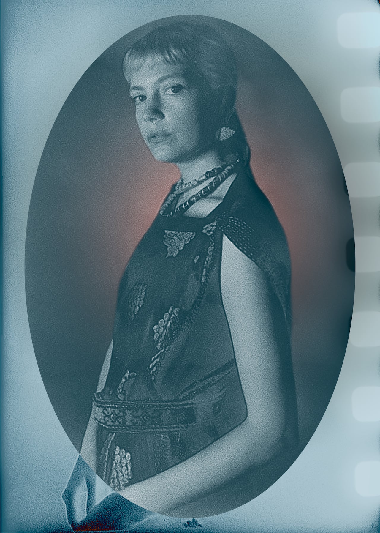 A film portrait of a person wearing a chunky necklace, whose hair is pulled back.