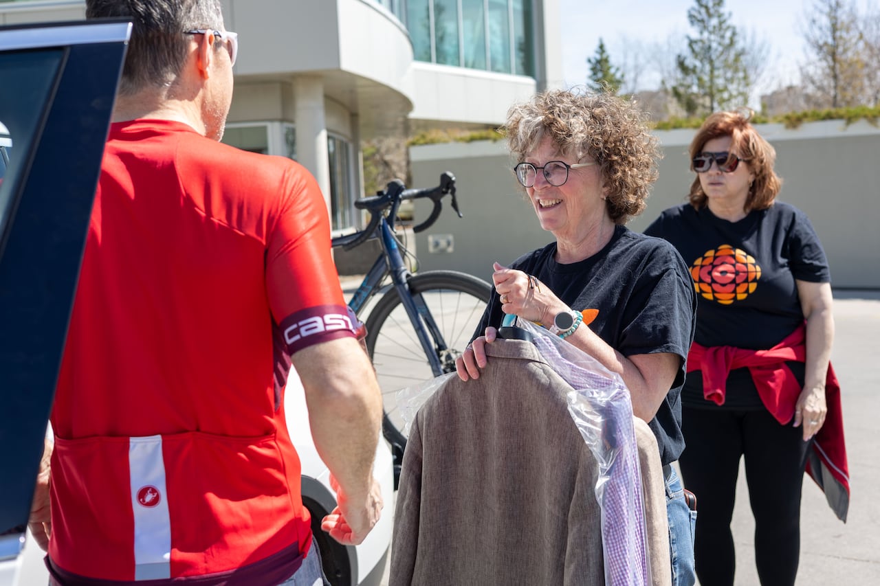 A woman receives a few suits from a man.
