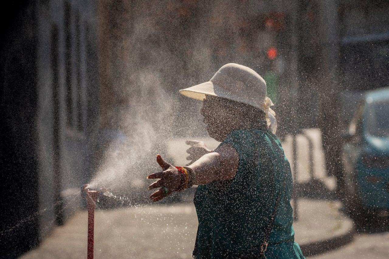 A person uses a misting station outside of Uprising Breads in Vancouver, British Columbia on Monday, June 28, 2021.