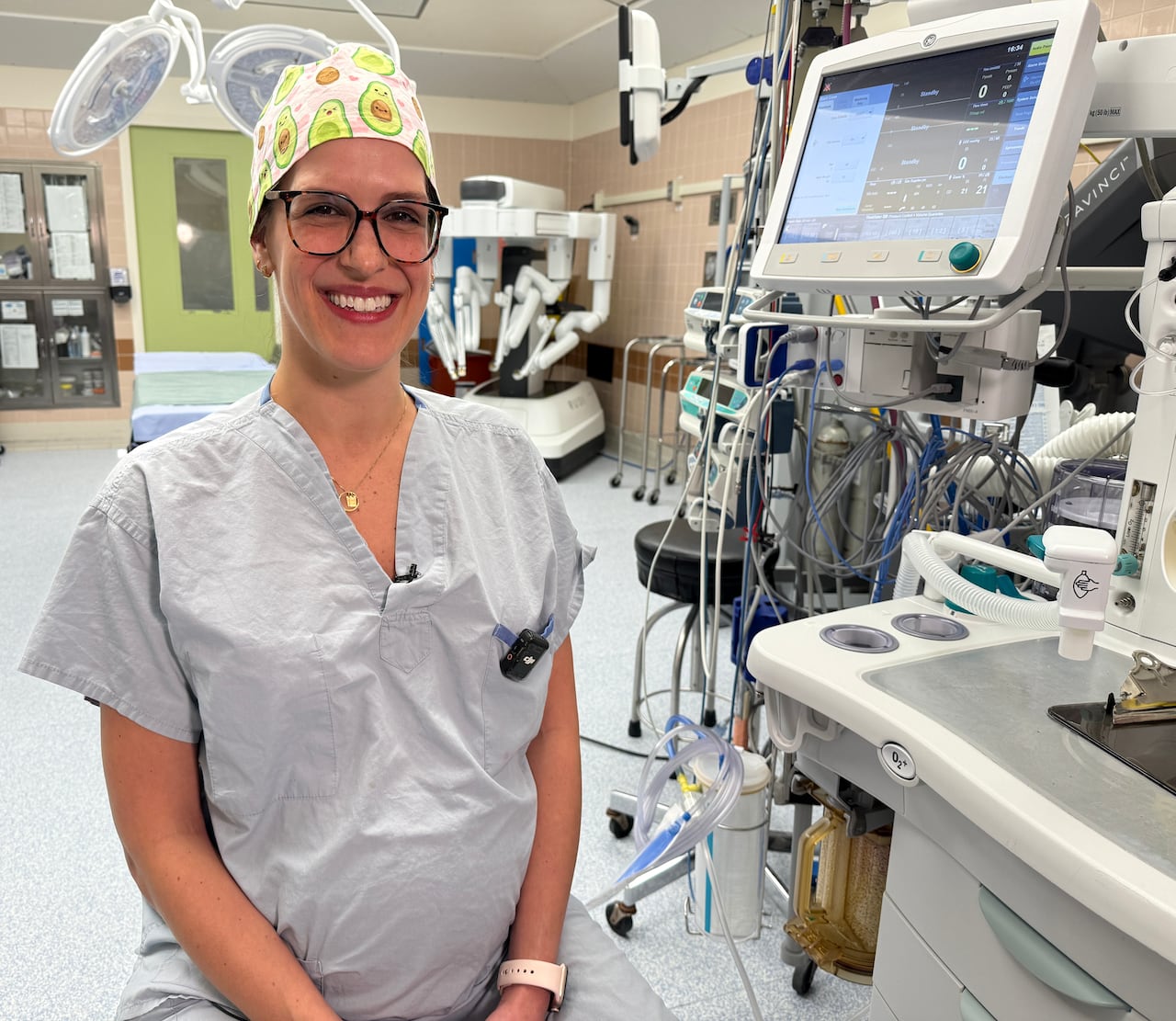 A woman wearing scrubs sits in a hospital operating room.