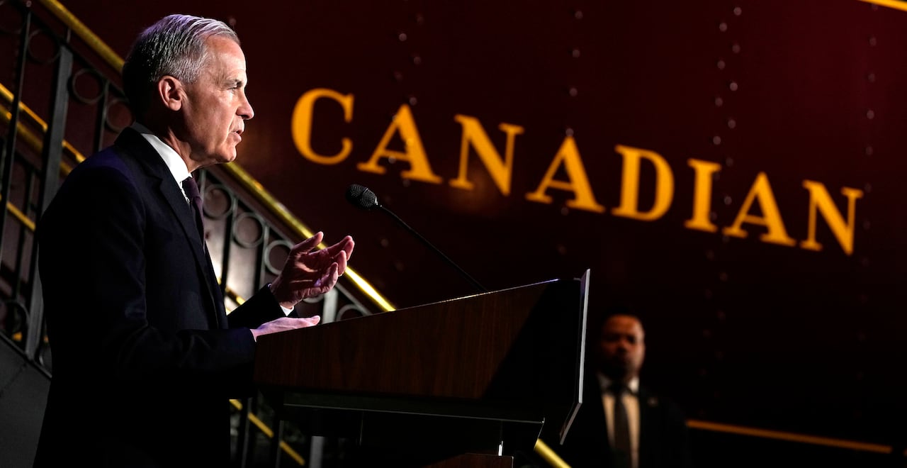 The Prime Minister speaks at a podium with the word "Canadian" shown in the background on a museum exhibit.