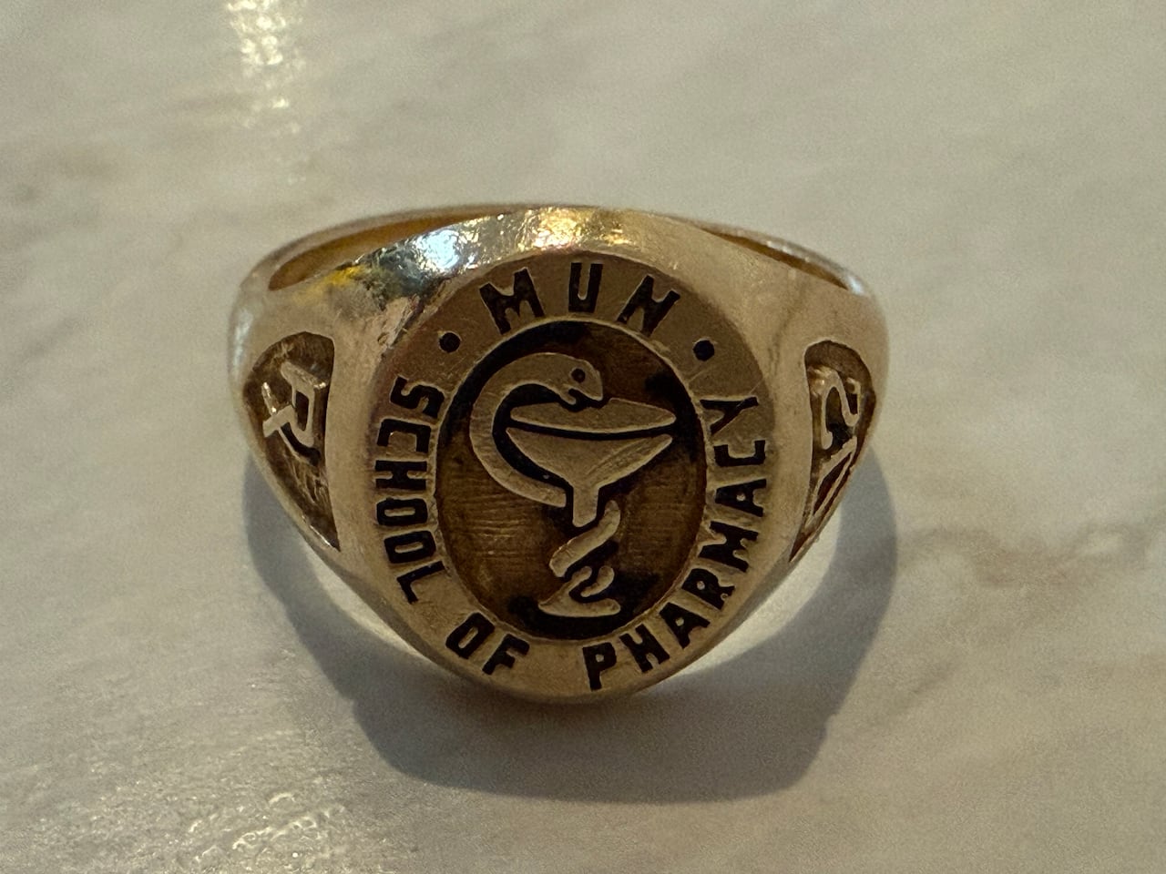 A golden ring with a pharmacist's crest engraved in it.