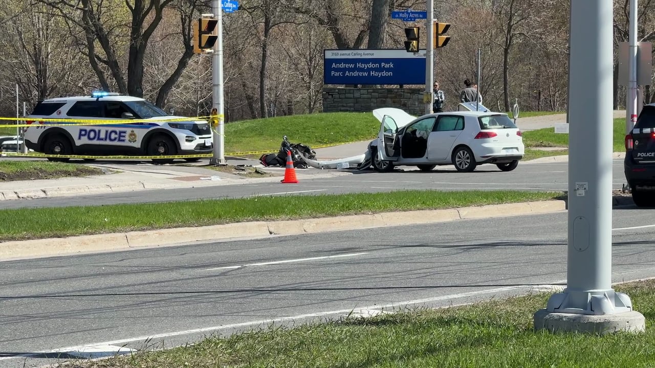A car with its hood up and a smashed up motorcycle