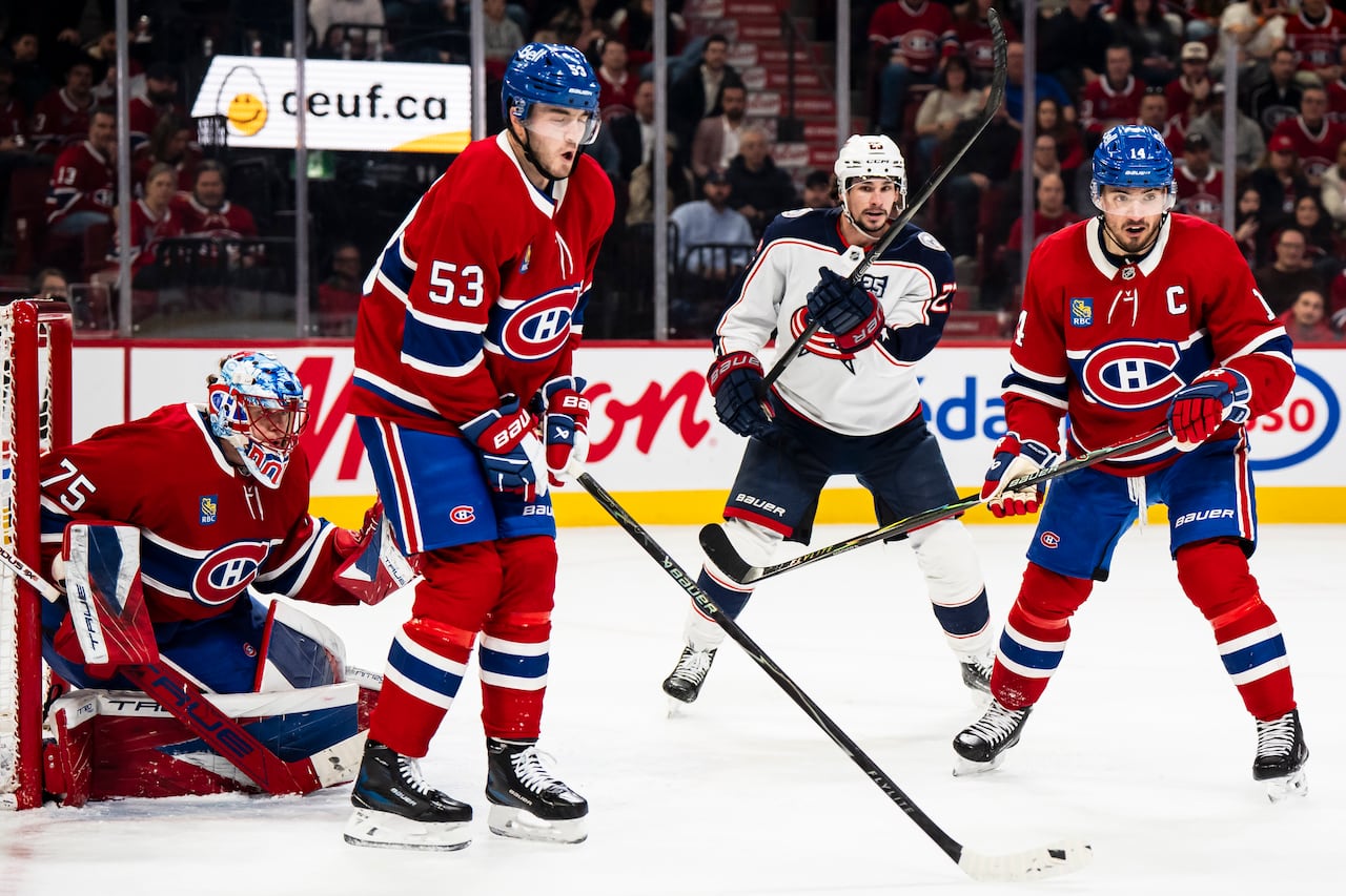 Professional hockey players are seen on the ice near the goalie.