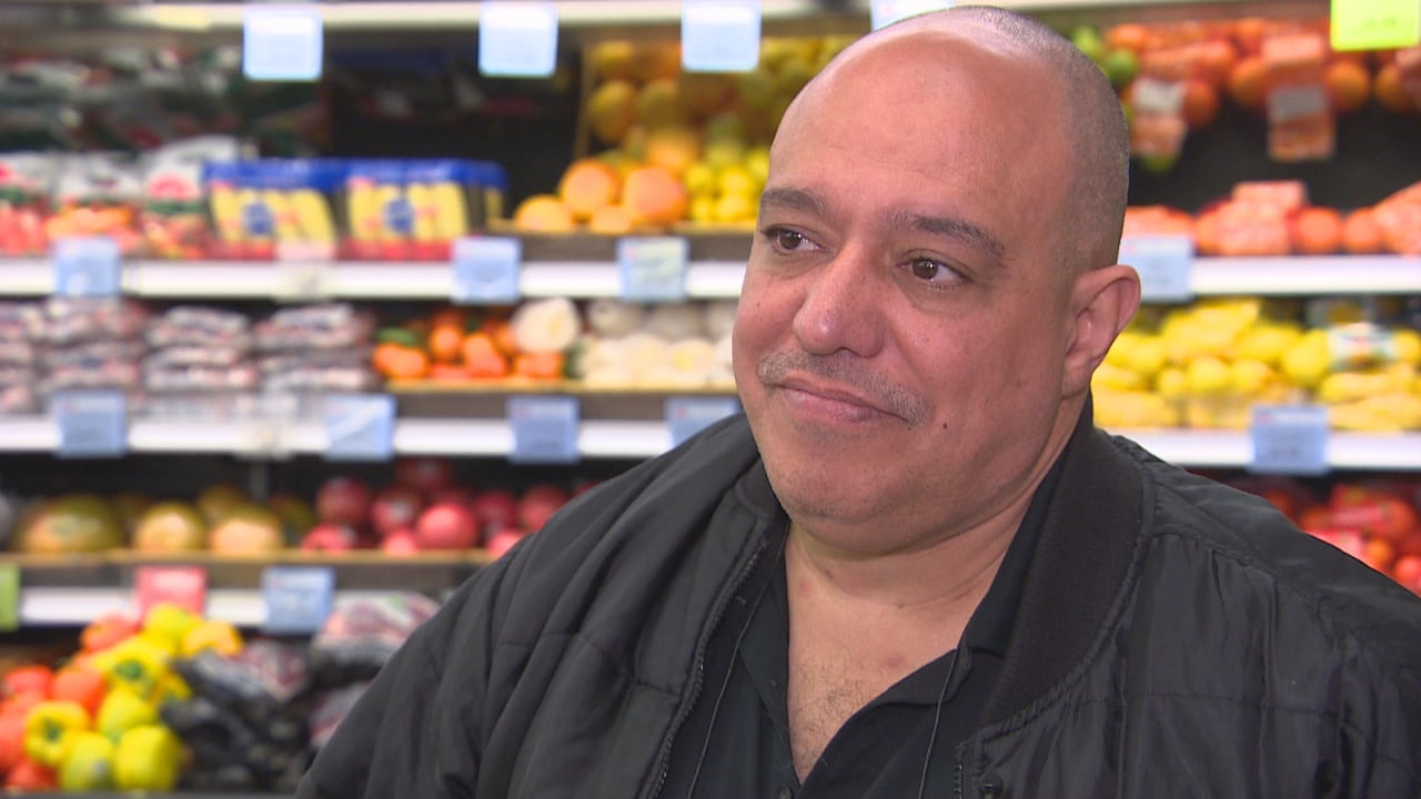 A man with a black jacket stands inside a grocery store.