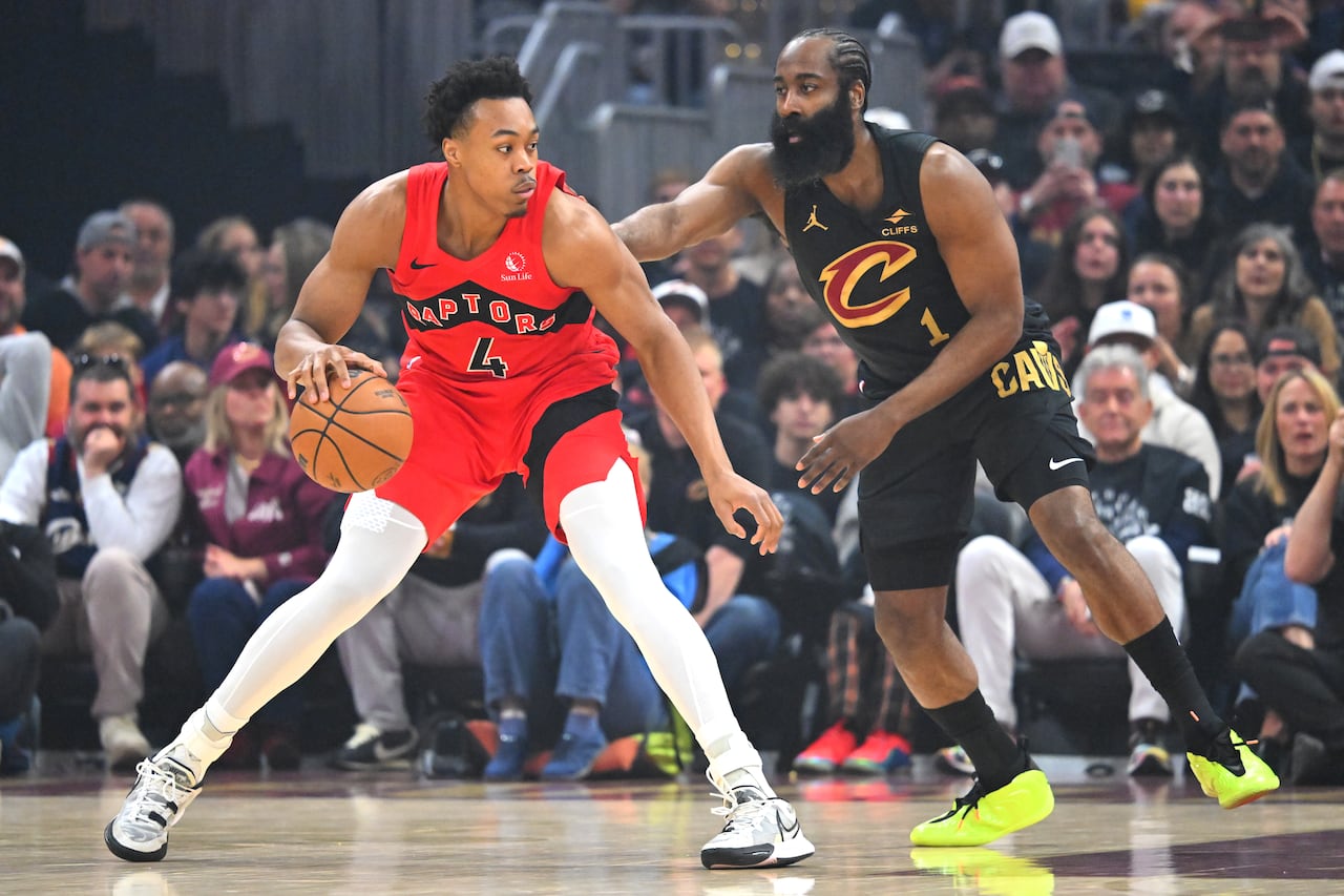 A basketball player dribbles the ball as a defender challenges them.