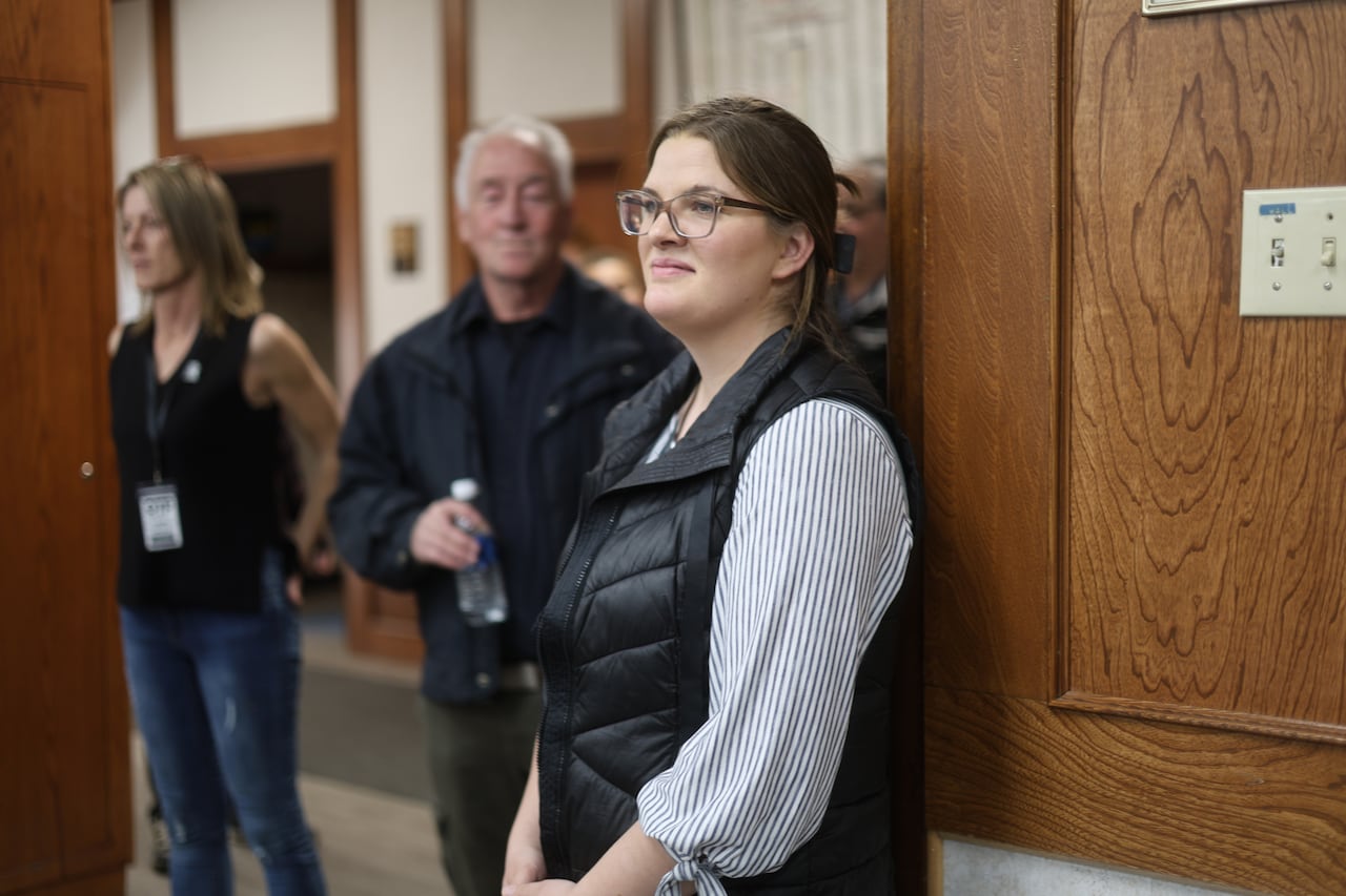 A woman stands at the back of a room.
