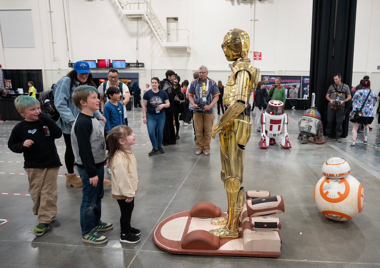 Attendees look at a golden droid.