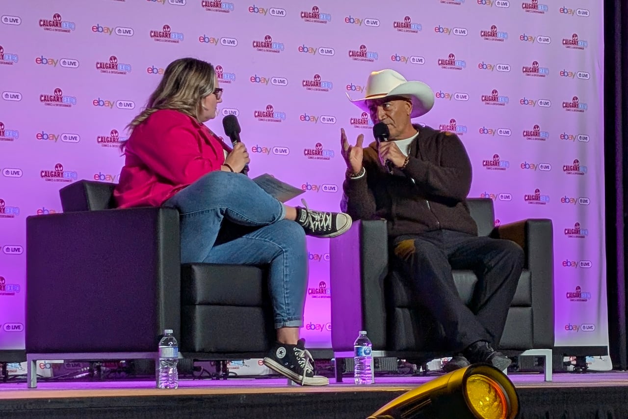 Two people speak on a stage.