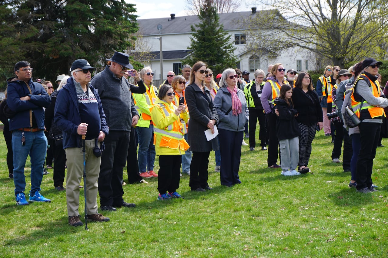 People attend a vigil in a park, many wearing high-vis uniforms.