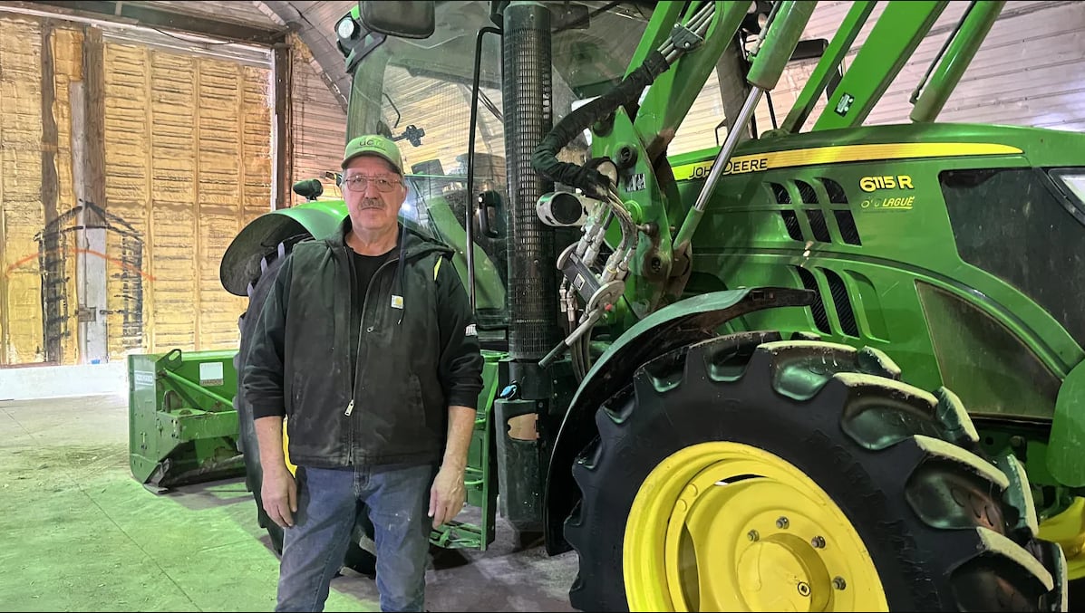 The vice-president of the Union of Franco-Ontarian Farmers stands in front of a farming vehicle.