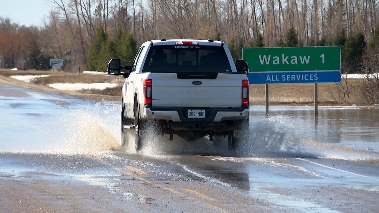 A truck splashes through water on a highway.