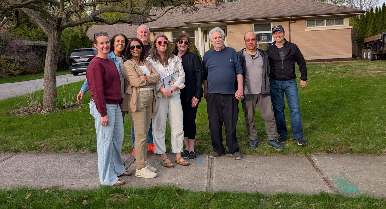 A group of people standing on a front lawn
