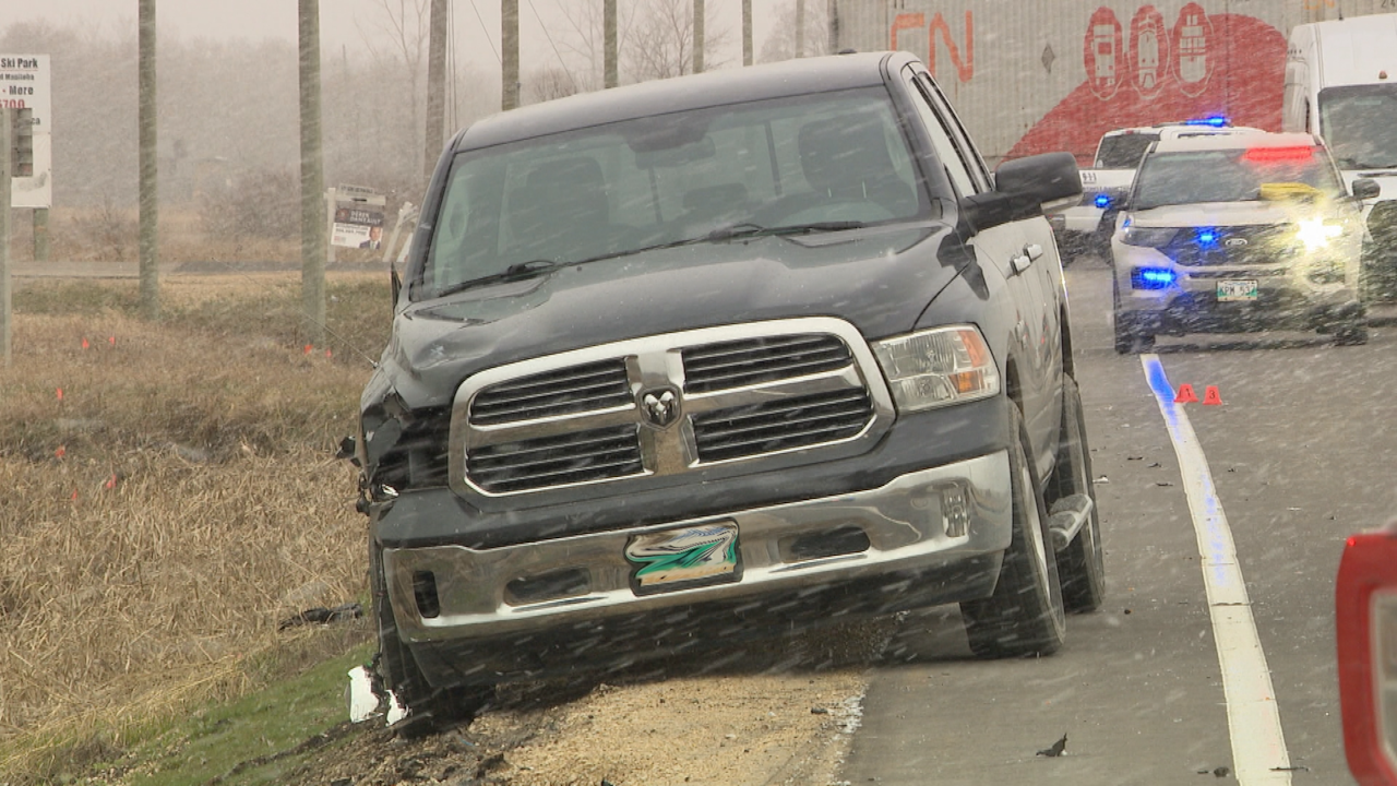 A pickup truck with a damaged front end is parked on the side of a road after a crash with cyclist