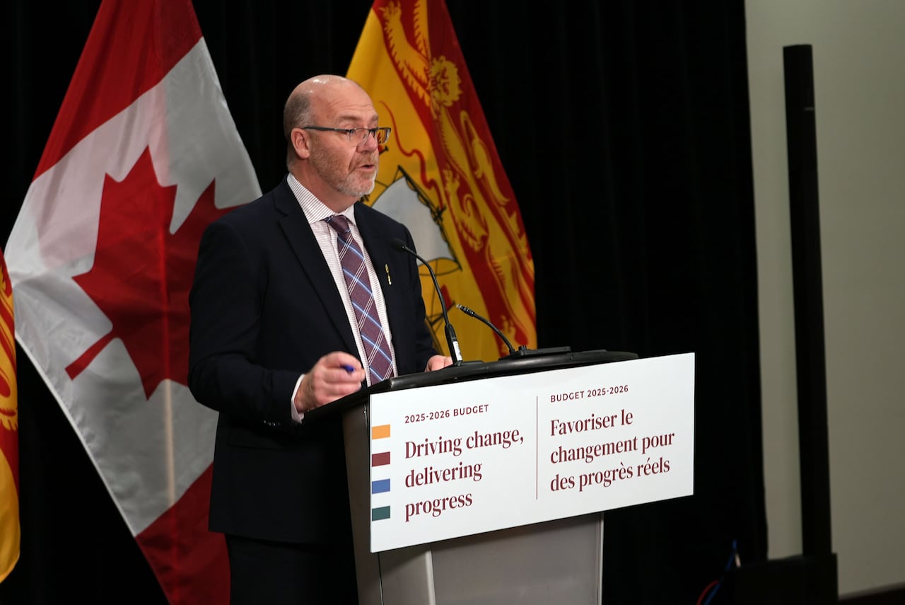 A man in a suit standing at a podium that says "Driving change, delivering progress"