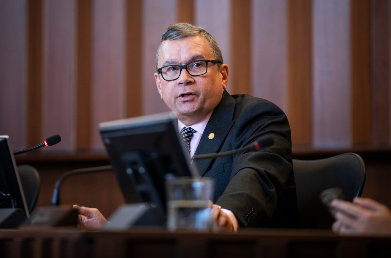 A man wearing a suit speaks in council chambers.