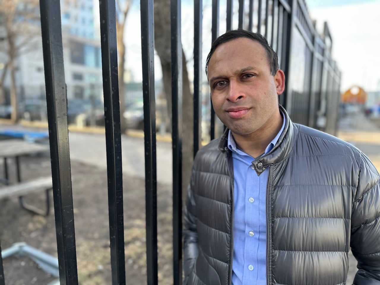 A man stands beside a gate.