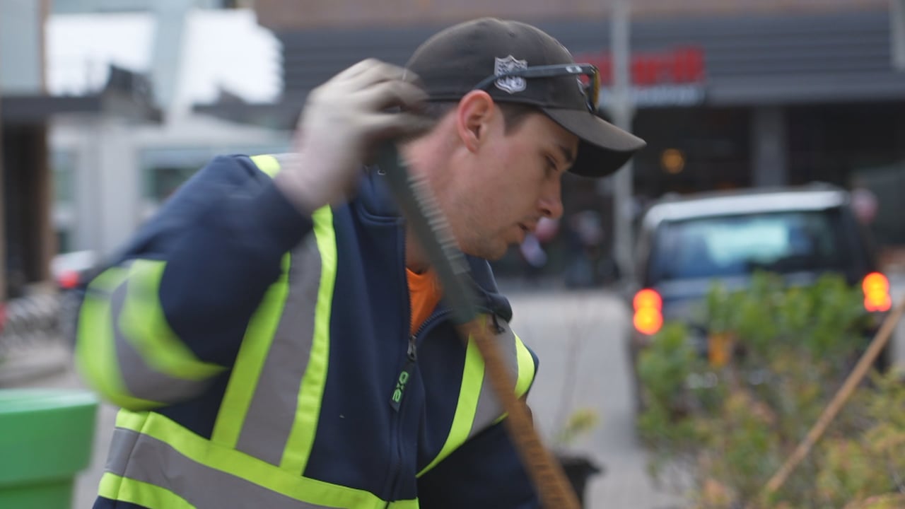 A man wearing a safety vest holding a rake.