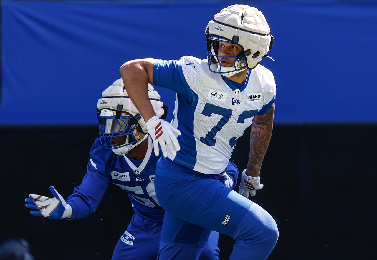 A football player looks to the side, over his shoulder, as he runs in practice.
