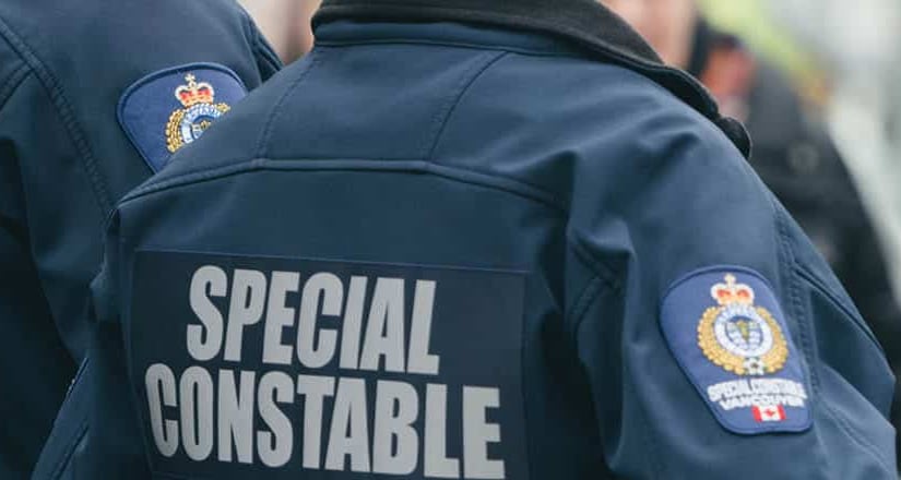 The backs of two people wearing jackets reading 'SPECIAL CONSTABLE' are shown.