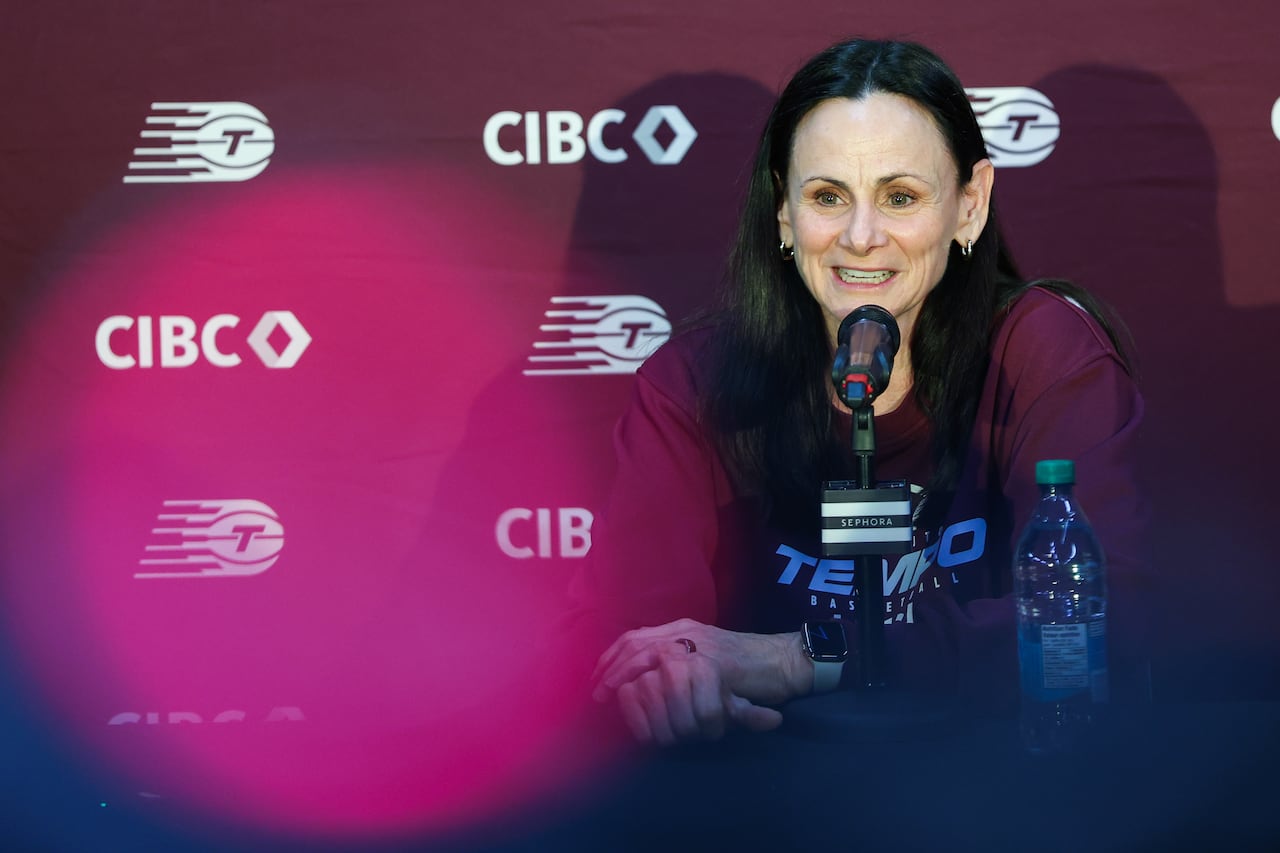 A woman is shown sitting behind a microphone with a maroon backdrop behind her with both the Toronto Tempo and CIBC logos on it.