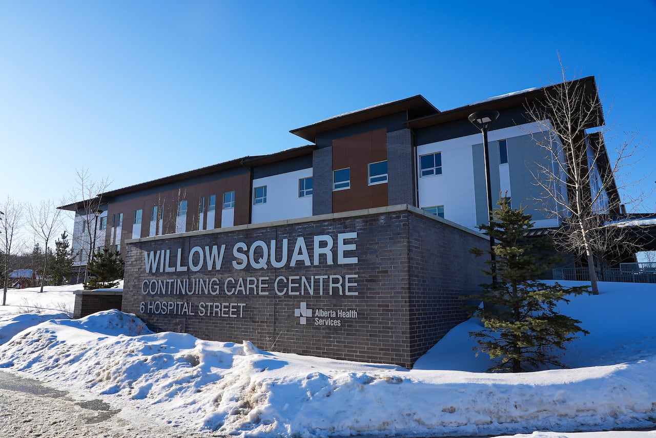 An orange and white building on a snowy hill with a large sign in front that says "Willow Square Continuing Care Centre."