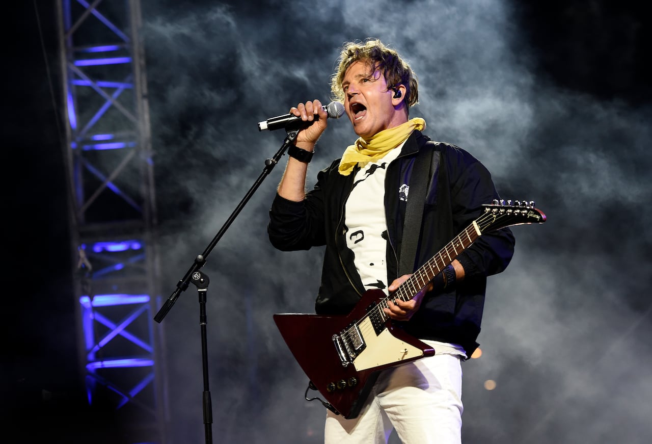 A singer with a guitar stands on stage.