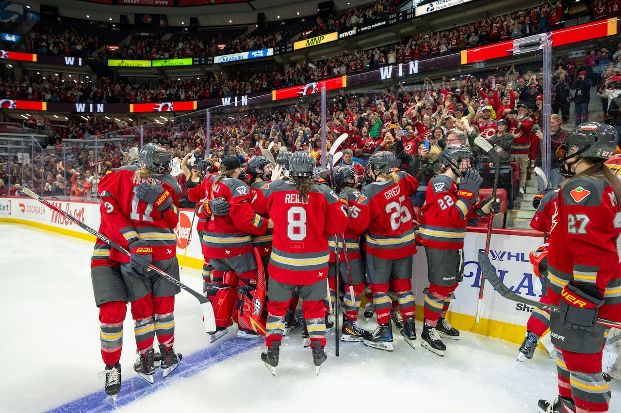 A hockey team celebrates on the ice.