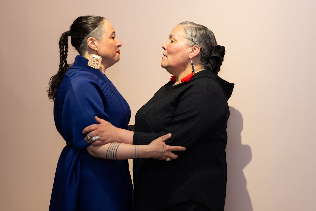 a woman in blue embraces a woman wearing black