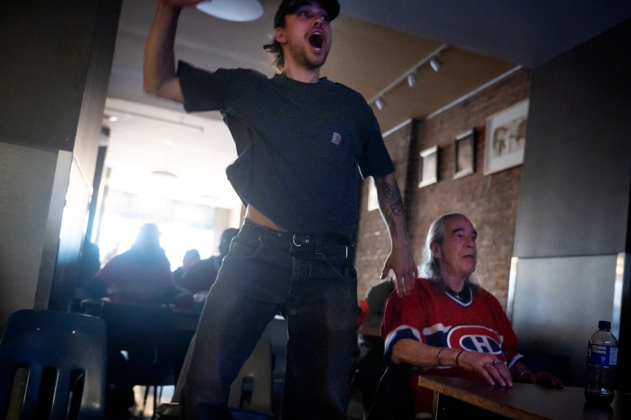 Case worker Teo Lapierre Langlais, left, and resident Allen Hayward react during Game 4 of second round NHL playoff hockey between the Montreal Canadiens and Buffalo Sabres at the Old Brewery Mission homelessness resource centre in Montreal on Tuesda