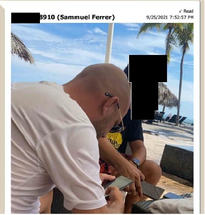 man looking at phone on a beach.