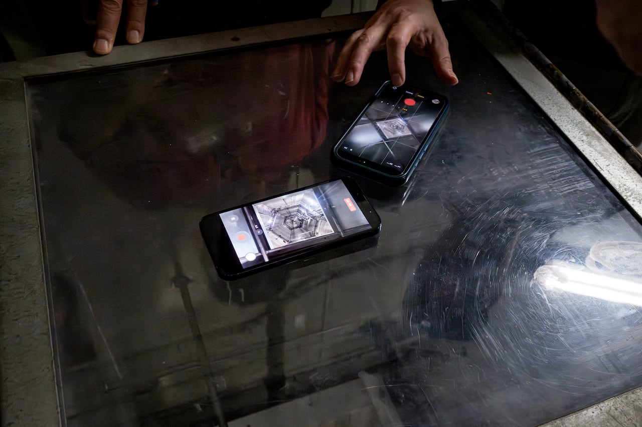 Two cellphones recording view of a shaft running nearly the full height of the CN Tower.