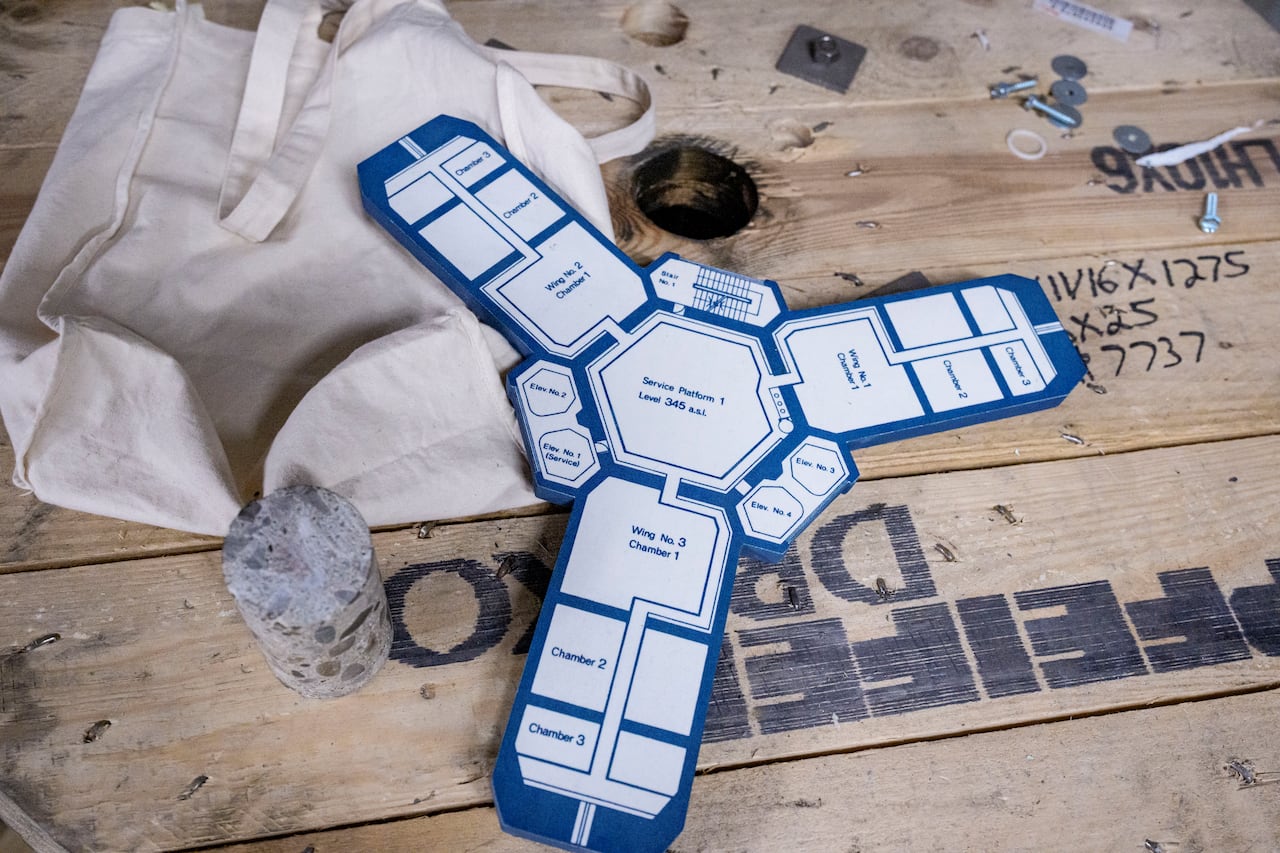 A cutout schematic of the CN Tower, next to a canvas bag on a wooden core sample of the tower itself.