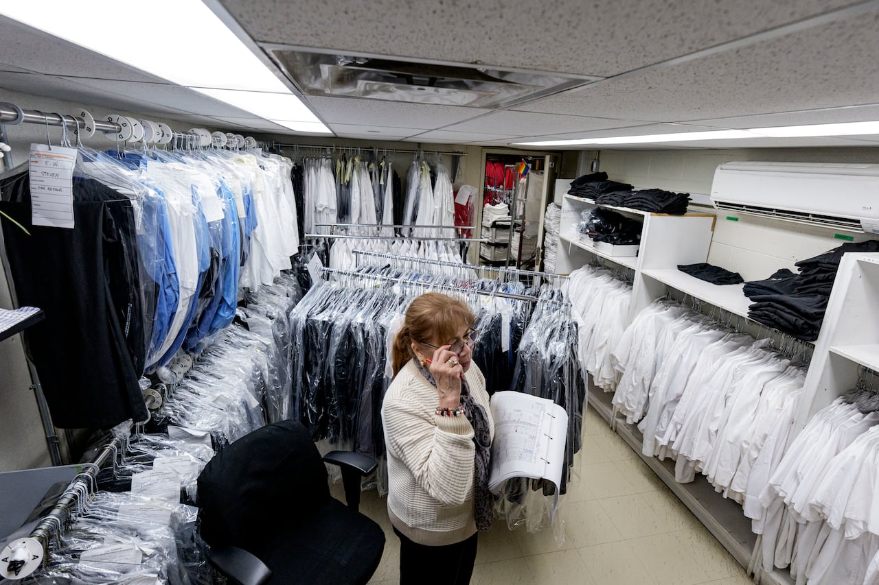 A woman standing in a room with clothing on racks.