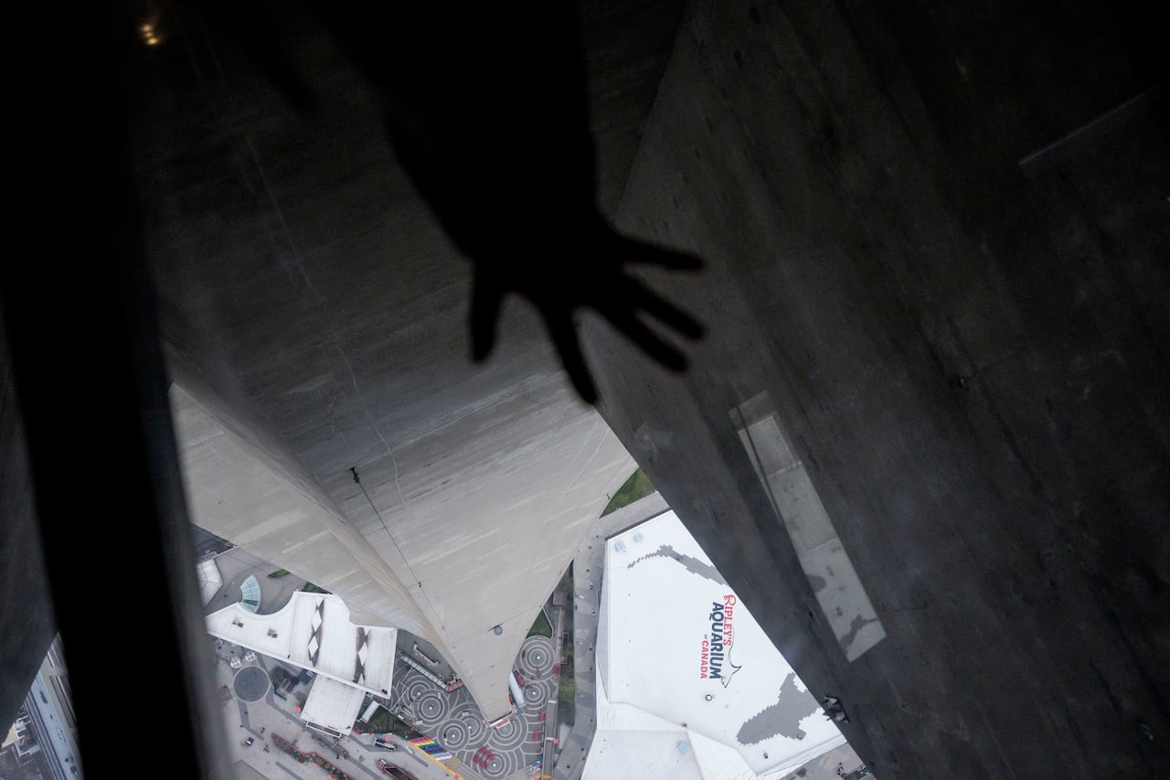 A hand in front of a glass floor of the CN Tower.