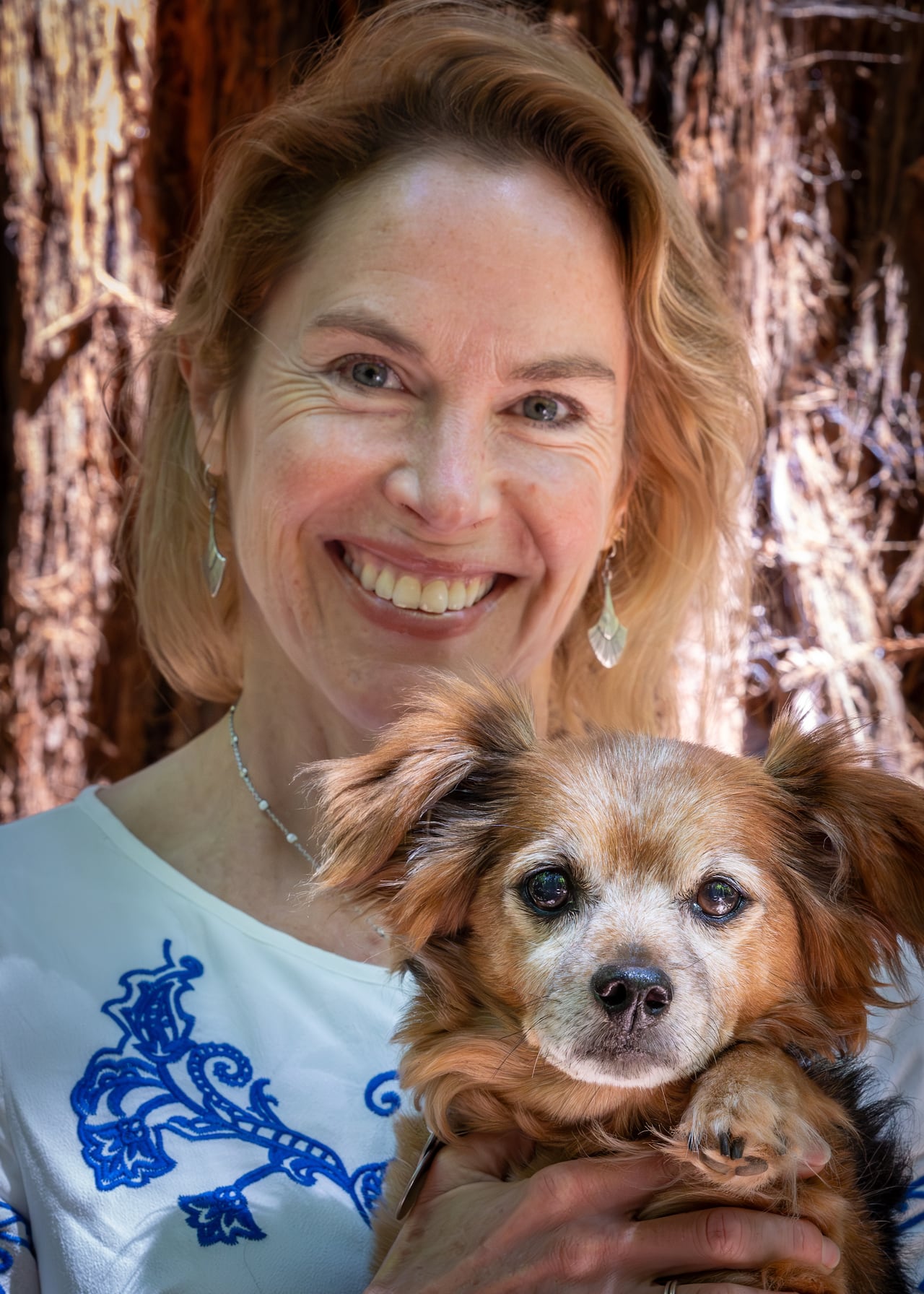 A woman is holding a small dog.
