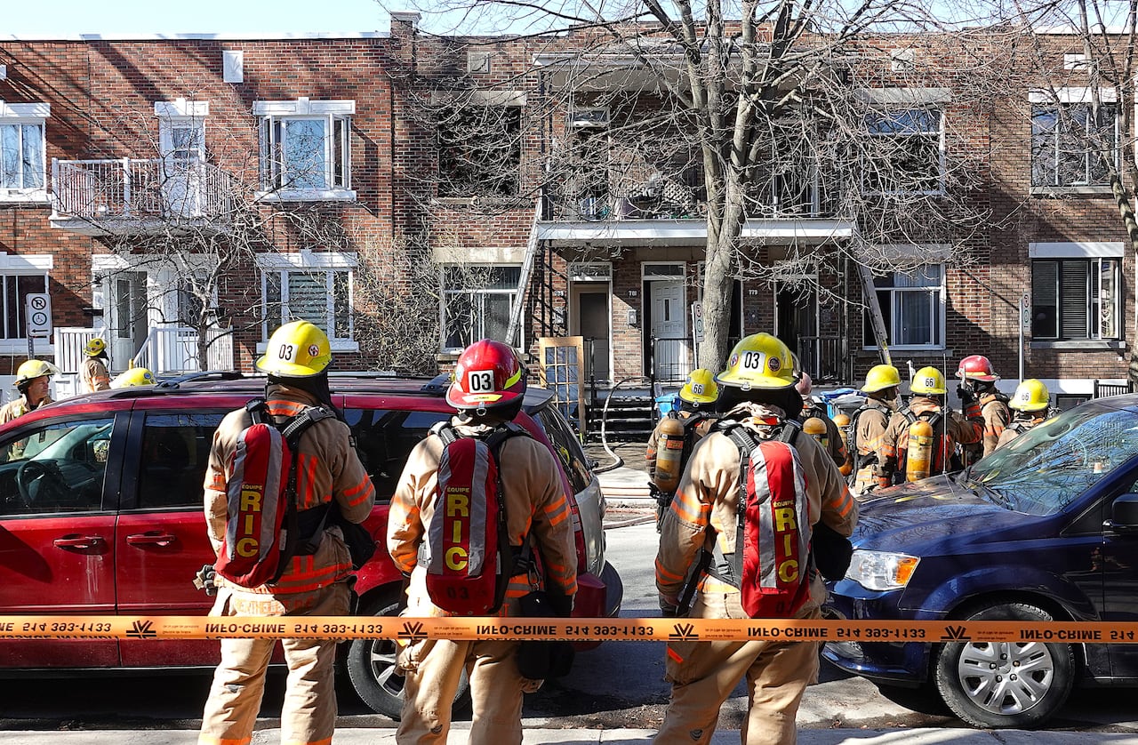Montreal firefighters stand outside a residential building in April 2026 following a fire in Verdun.