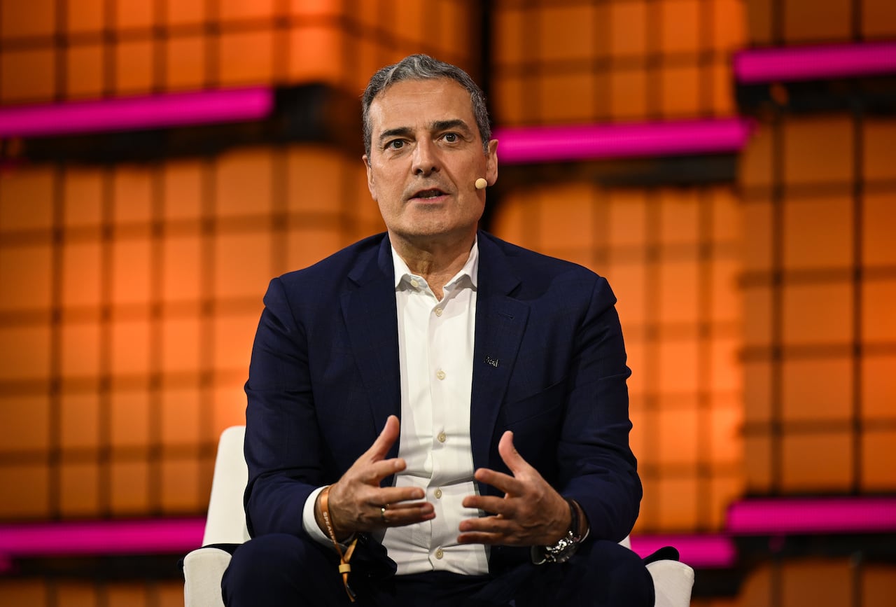 A man in a suit speaks on stage at a conference.