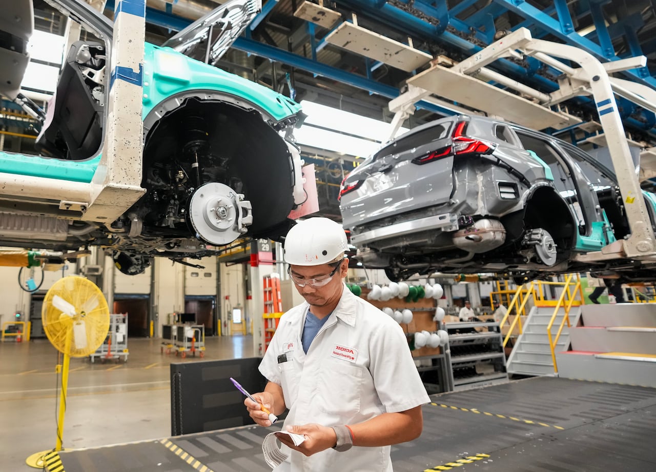 a man in a hard hat works on the floor at the honda plant in alliston