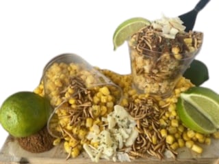 Two plastic cups filled with corn and dried mealworms with lime slice garnishes.