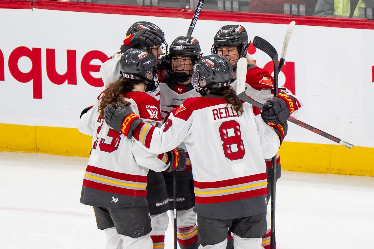 Several hockey players celebrate a goal on the ice.