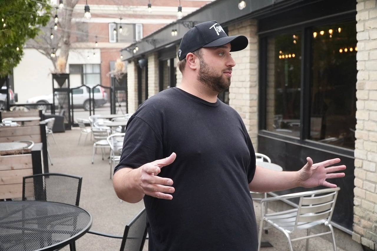 A man gesticulating while outdoors on a patio.