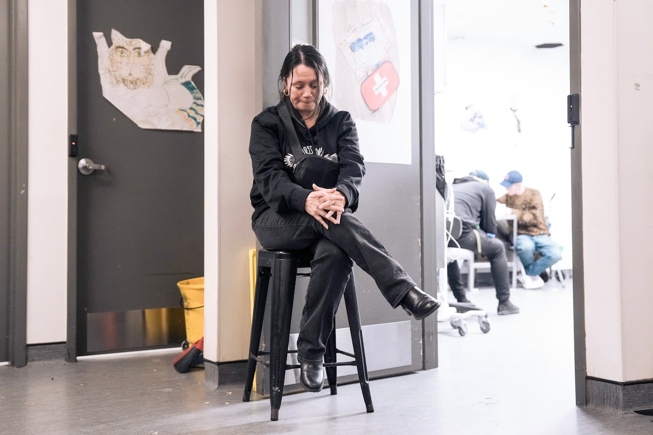 Woman sits on a stool by a door