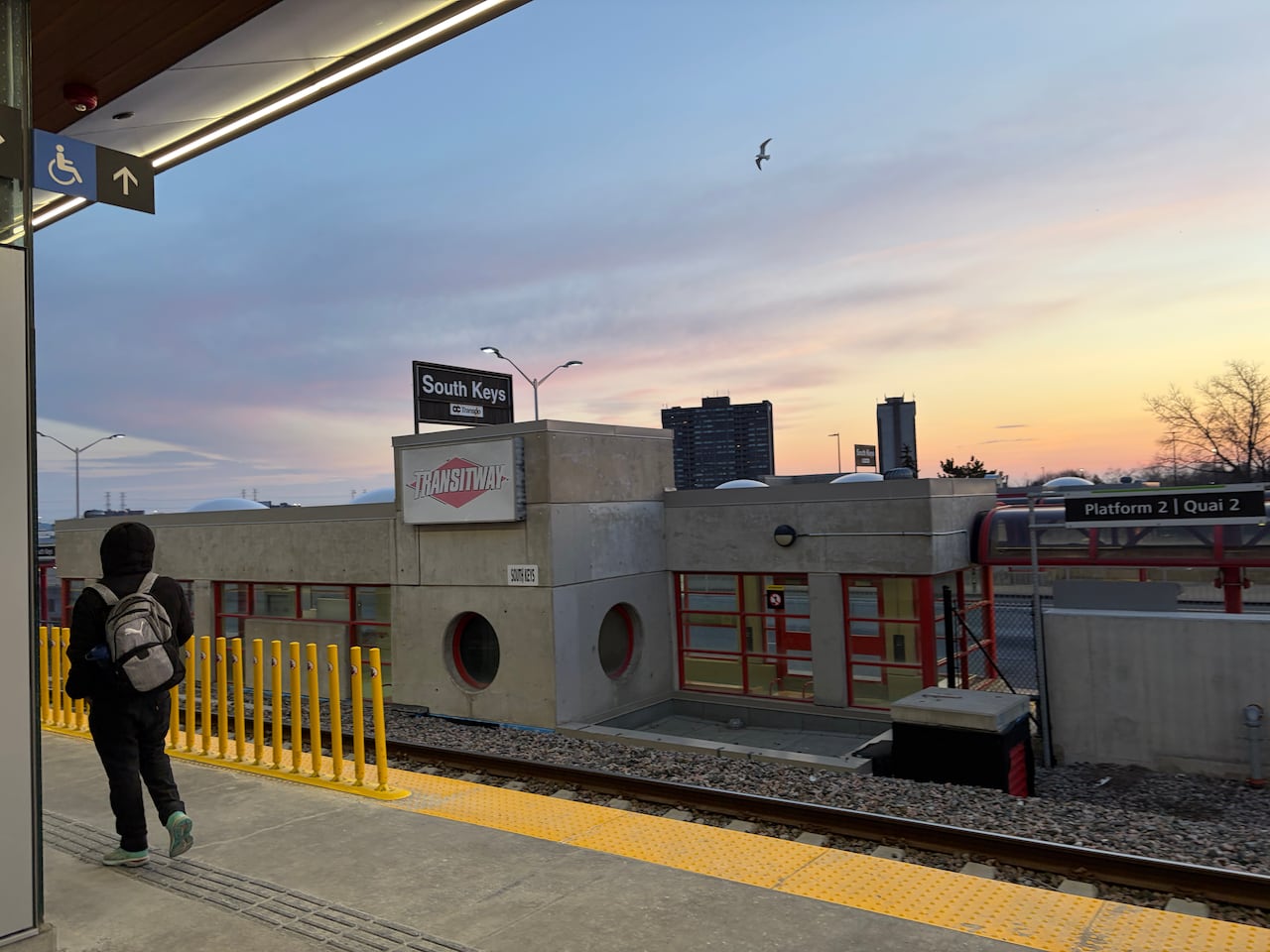 A transit station with both trains and buses on a sunny spring morning.