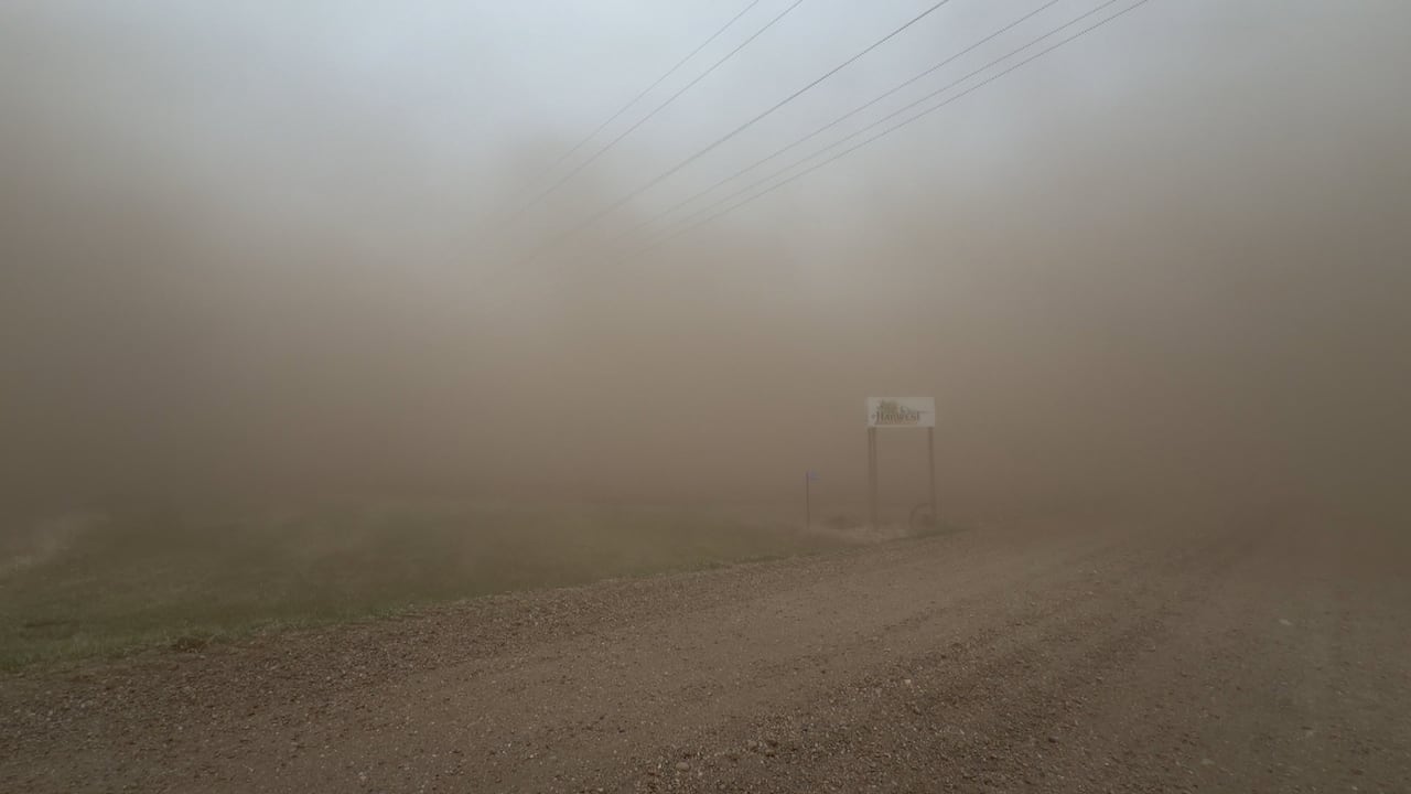 A dust storm obscures a sign near a farm