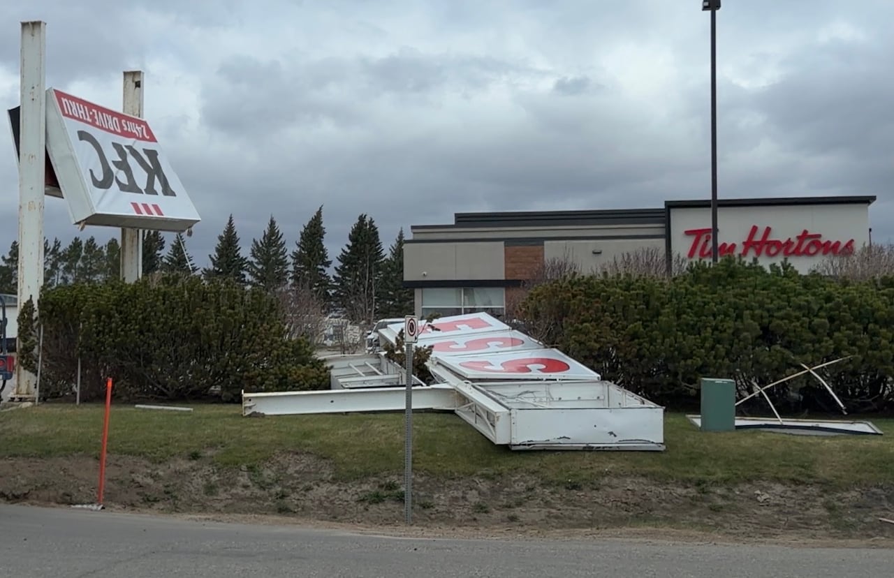 Signs from an Esso gas station and KFC restaurant are damaged by wind.