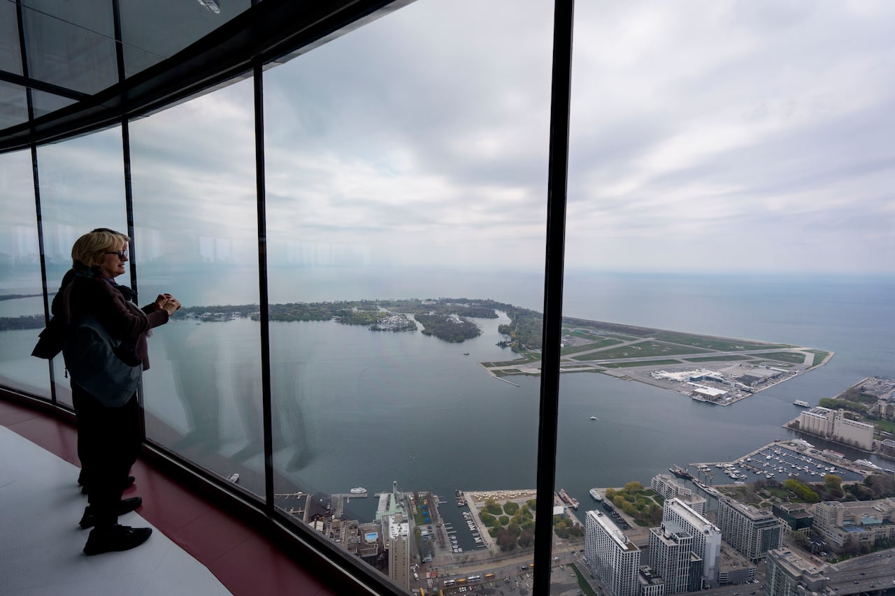 Attendees look out towards Toronto Island Airport from the observation deck of the CN Tower on May 13, 2026. The landmark is participating in Doors Open Toronto, where members of the public get rare access to the city’s architecturally significant bu