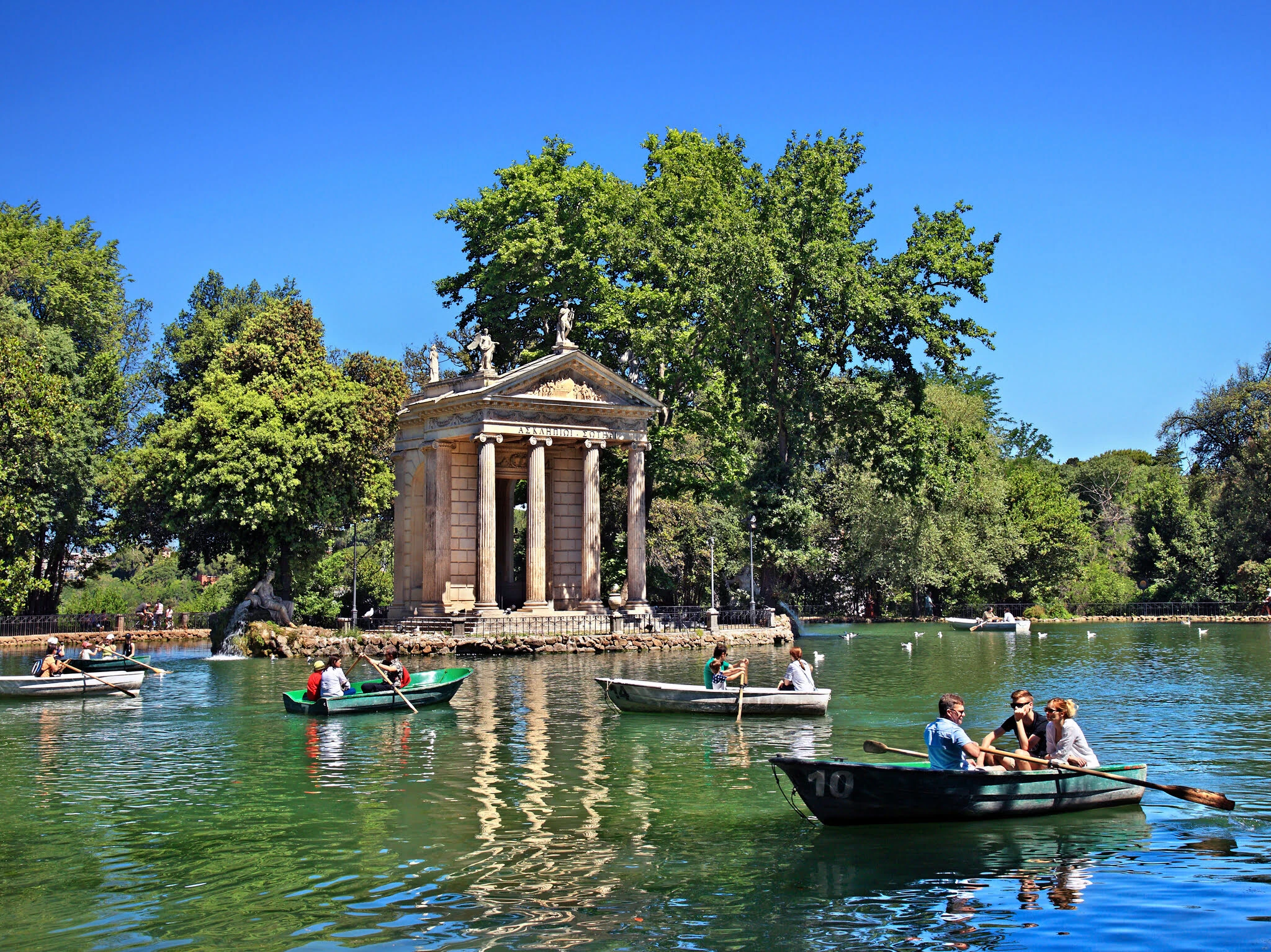 ROME, ITALY- Visitors rowing their boats in the lake of the Villa Borghese gardens, next to the 18th century "Temple of Asclepius (Aesculapius).